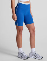 blue high-waisted biker shorts with a 5" inseam, waistband colorblock panels, and
contrast piping detail on leg.